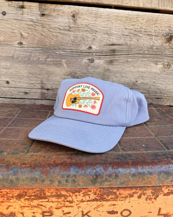 Support Live Music Hat displayed on a rustic surface with a guitar logo, perfect for music lovers.