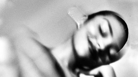 Artistic black and white portrait of a woman with a serene expression, emphasizing light and shadow.