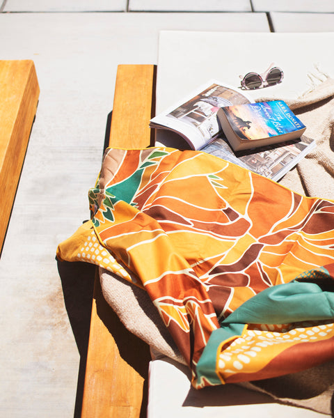 Alpenglow Wander Towel draped on a lounge chair by the pool, showcasing warm tones and mountain vibes.