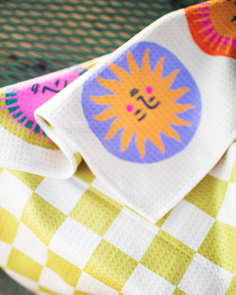 Always Sunny Kitchen & Tea Towel featuring colorful sun designs on a cheerful yellow and white checkered pattern.