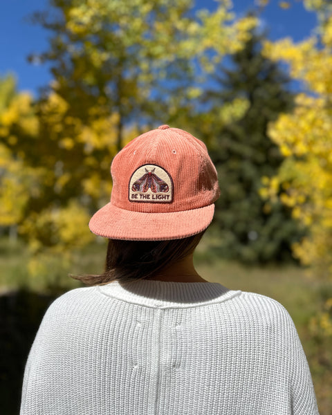 Be The Light Hat worn by a woman outdoors, showcasing its design in a natural setting.