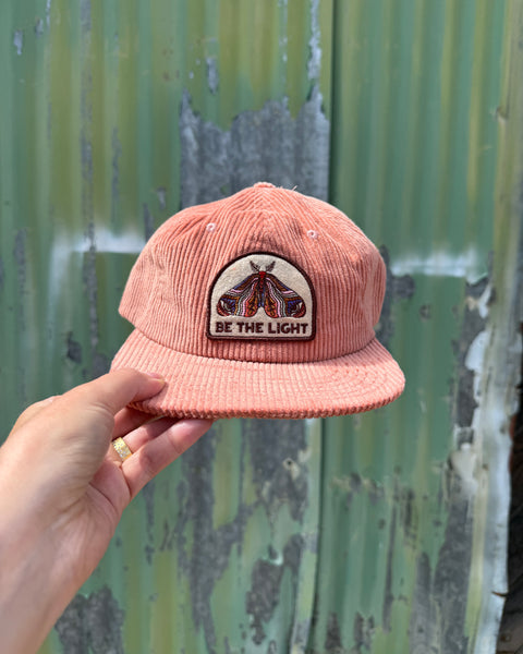 Be The Light Hat shown in hand with a corduroy fabric and embroidered design, perfect for everyday wear.