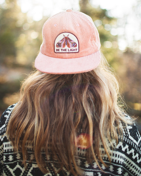 Be The Light hat with painted moth design, 6-panel snapback, flat brim, in a scenic outdoor setting. Trek Light style for all.