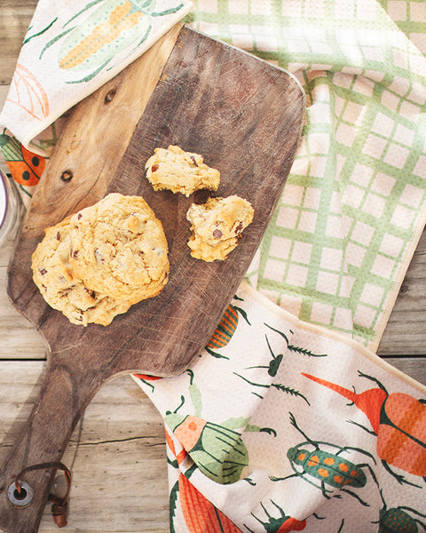 Beetlemania Kitchen & Tea Towel styled with cookies and milk on wooden surface, showcasing modern garden-themed design.