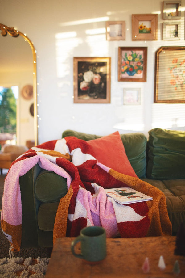 Cozy Bernie Blanket made from recycled clothing materials, handwoven and versatile, draped over a couch for a warm, inviting look. By Trek Light.