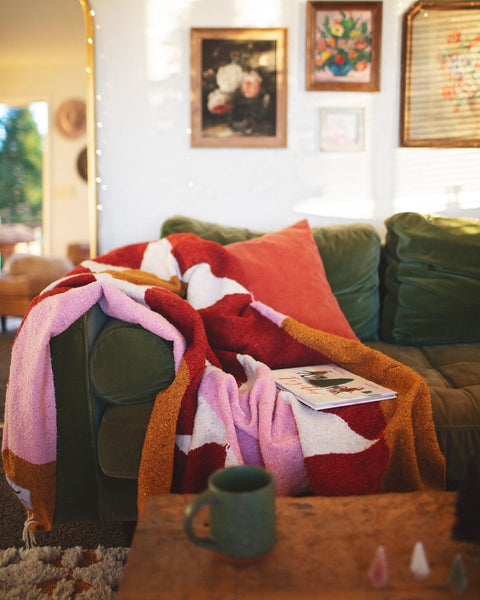 Cozy Bernie Blanket made from recycled clothing materials, handwoven and versatile, draped over a couch for a warm, inviting look. By Trek Light.
