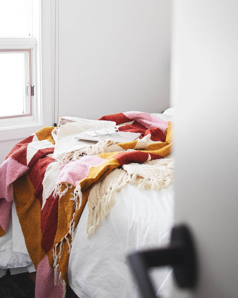Cozy Bernie Blanket draped over a bed with books and glasses nearby, perfect for relaxation and comfort.