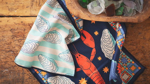 Patterned napkins with oyster and lobster designs on rustic wood surface
