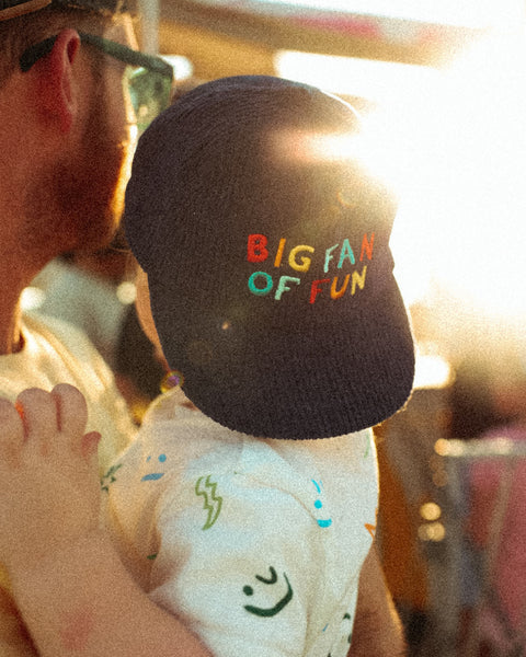 Child wearing a Big Fan Of Fun Kids Hat in a sunny outdoor setting, perfect for playground and parties.