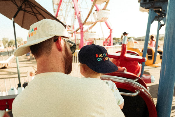 Big Fan Of Fun Hat - Twinsie Set worn by adult and child at amusement park, showcasing matching hats.