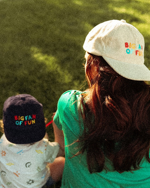 Big Fan Of Fun Hat Twinsie Set: cream and navy corduroy caps with colorful stitching, worn by an adult and a child on grass.