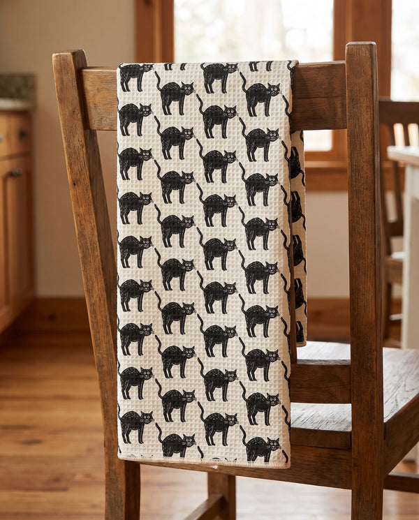 Black Cats waffle kitchen tea towel draped over a wooden kitchen chair, front print facing out