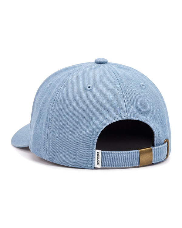 Back view of the Book Worm Hat, a light blue washed denim cap with a brass strap buckle, on white.