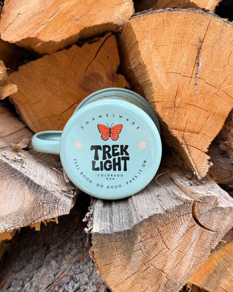Butterfly Beauty Mug - Enamel 16oz Mug resting on wood logs, featuring a vibrant butterfly design.