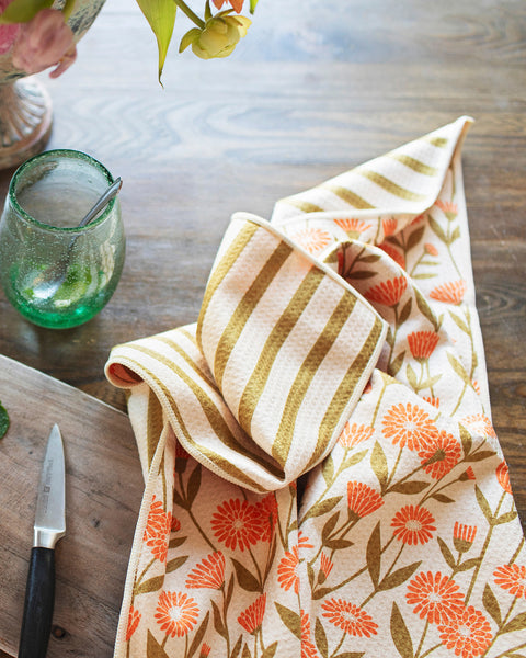 Calendula Flowers Kitchen & Tea Towel displayed with fresh fruits on a wooden table.