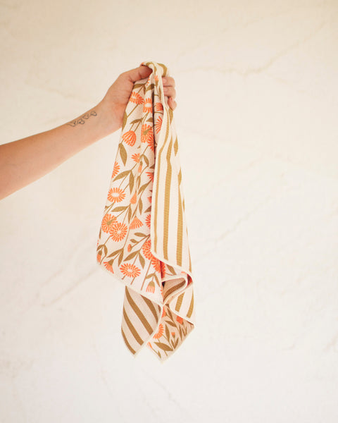 Calendula Flowers Kitchen & Tea Towel held in hand, showcasing vibrant floral design on microfiber material.