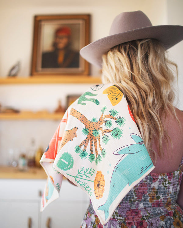 California Kitchen & Tea Towel with vibrant desert patterns on a woman's shoulder, showcasing style and functionality.