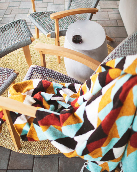 Cascade Blanket draped over a chair with a glass of red wine, perfect for cozy outdoor moments.