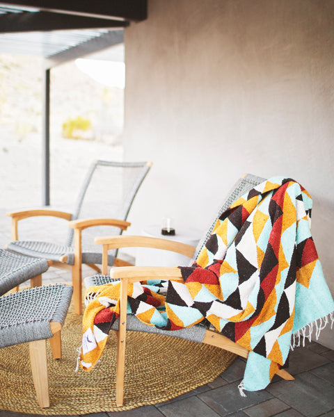 Cascade Blanket draped over a chair, showcasing geometric patterns in calm colors, perfect for cozying up outdoors.