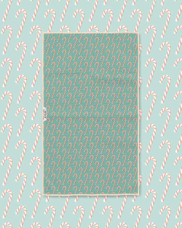 Candy cane print kitchen tea towel styled on a matching teal candy cane backdrop