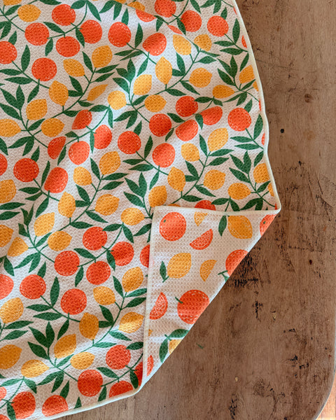 Saved By Citrus Kitchen & Tea Towel featuring vibrant orange and lemon patterns on a textured fabric.