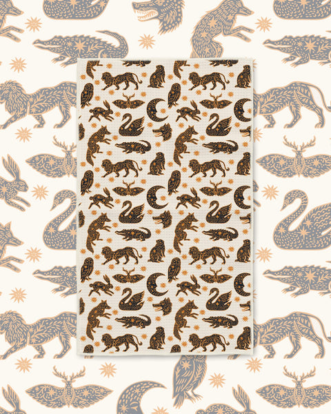 Cosmic Creatures Kitchen & Tea Towel with swans, prowling animals, moths and crescent moons in black and gold on cream