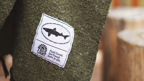 Trek Light patch on green fabric with shark design and motto 'Feel Good. Do Good. Pass It On.'