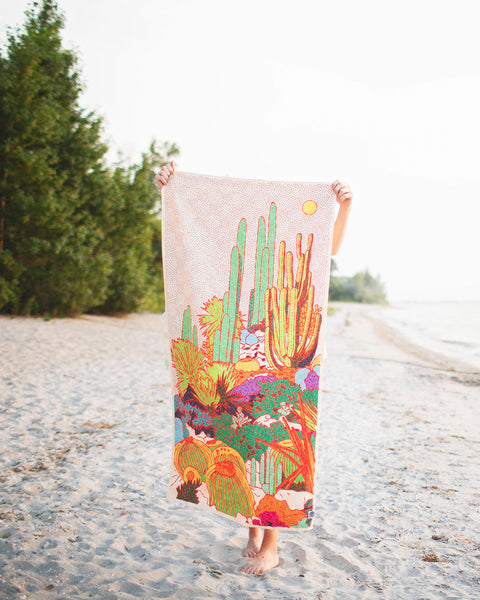 Desert Dreams Wander & Travel Towel displayed on a beach, showcasing vibrant Southwest design and quick-dry material.