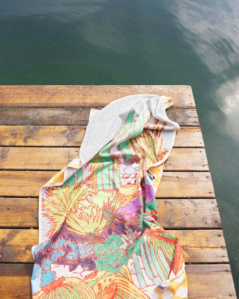 Desert Dreams Wander & Travel Towel on a wooden dock over water, showcasing vibrant desert-themed design.