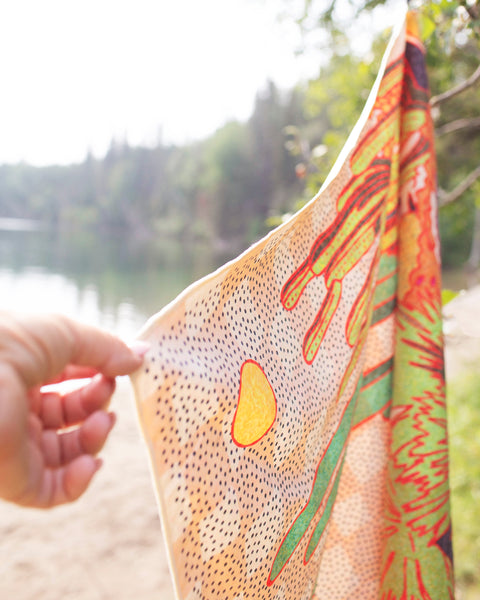Desert Dreams Wander & Travel Towel hanging by a serene lake, showcasing vibrant design and quick-dry material.