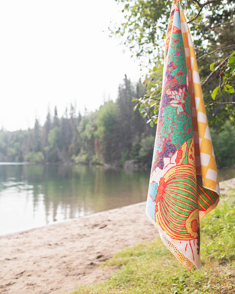 Desert Dreams Wander & Travel Towel hanging by the lake, showcasing vibrant design and quick-dry fabric.