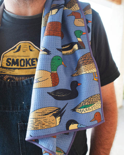 Ducks In A Row Kitchen & Tea Towel featuring colorful duck illustrations on a vibrant blue background.