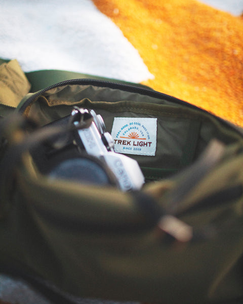 Everyday Fanny Pack (Fern) interior showing Trek Light label and camera gear.