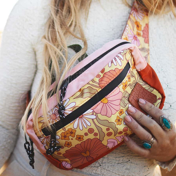 Colorful floral Trek Light Everyday Fanny Pack worn as a crossbody bag, showcasing its stylish design and spacious, water-resistant features.