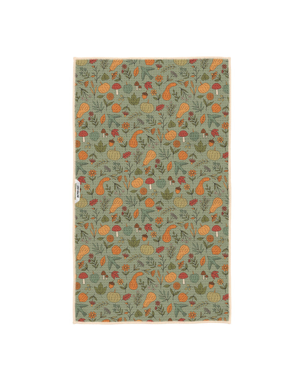 Fall Harvest kitchen tea towel on sage green background with orange pumpkins, gourds, mushrooms, acorns, leaves and birds