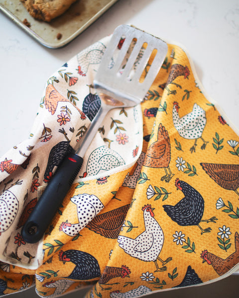 Farmhouse Chicken Kitchen & Tea Towel with decorative chicken patterns and a spatula on a marble countertop.