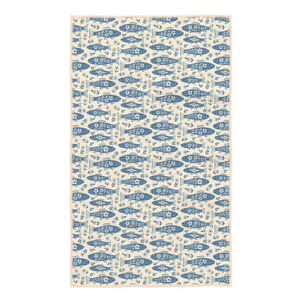Beige kitchen tea towel covered in blue floral trout fish arranged in rows with small white flowers between them