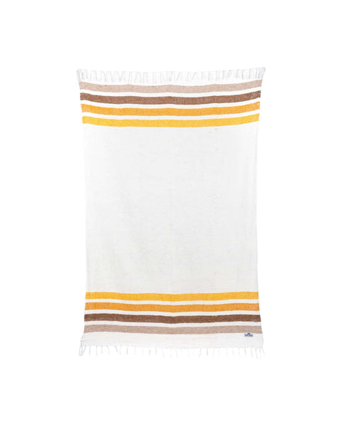 Golden Age Blanket in cream woven fabric with tan, brown and yellow stripes near each end and fringed edges, on white.