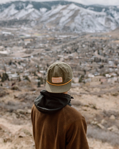 Person wearing a Grateful Every Day Hat while overlooking a scenic mountain view.