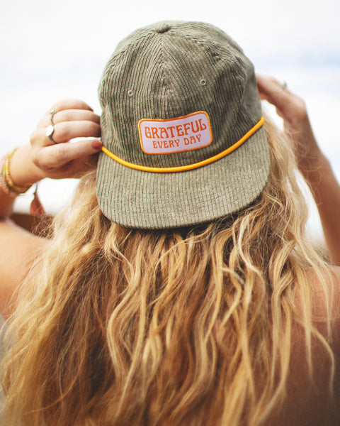 Person wearing Trek Light Grateful Every Day hat with flat brim and corduroy style, perfect for expressing gratitude and style.