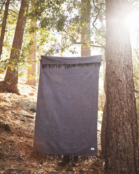 Greyson Blanket displayed outdoors, showcasing its sleek design and soft, cuddly texture against a natural backdrop.