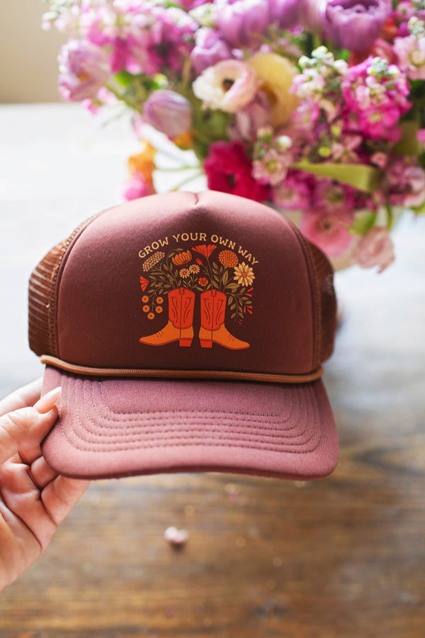 Hand holding the Grow Your Own Way Hat featuring floral design and boots, perfect for stylish comfort.