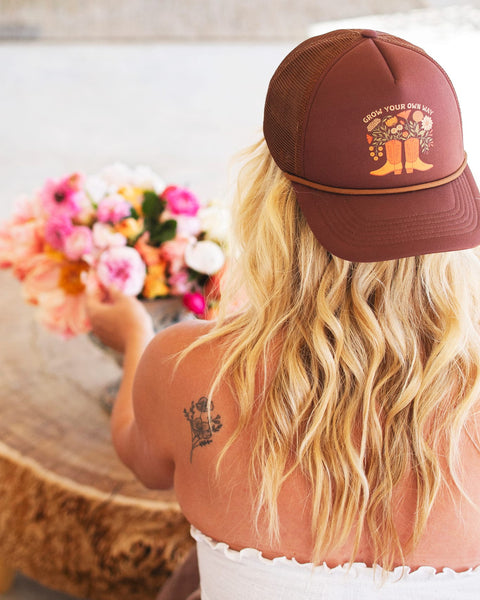 Woman wearing a Grow Your Own Way Hat, stylishly designed with floral graphics and adjustable fit.