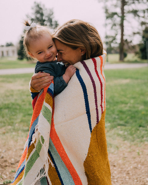 Mother and child wrapped in a colorful blanket, enjoying time outdoors with the Halley's Comet Blanket.