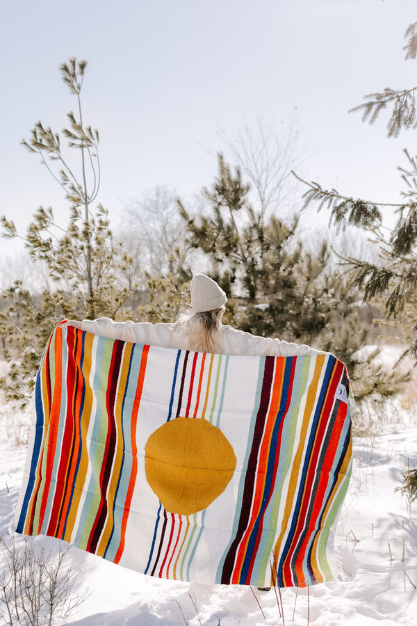 Person holding colorful Halley's Comet Blanket by Trek Light in snowy outdoors