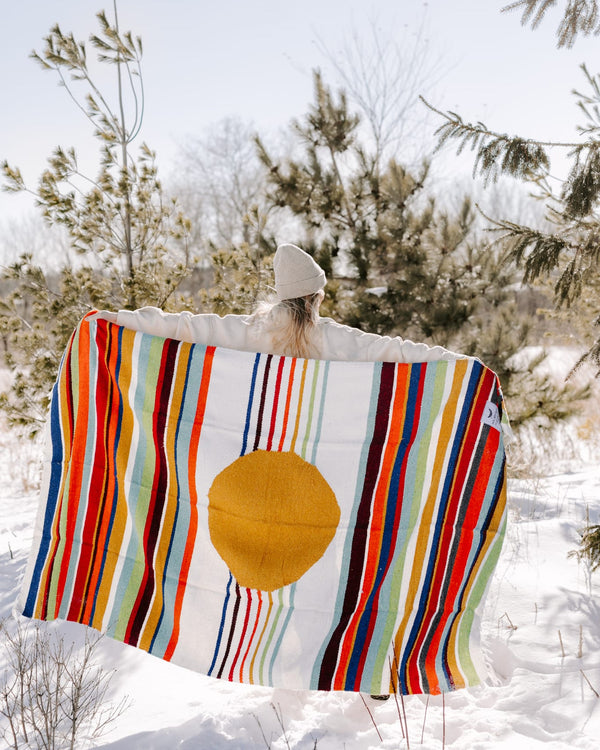 Person holding colorful Halley's Comet Blanket by Trek Light in snowy outdoors