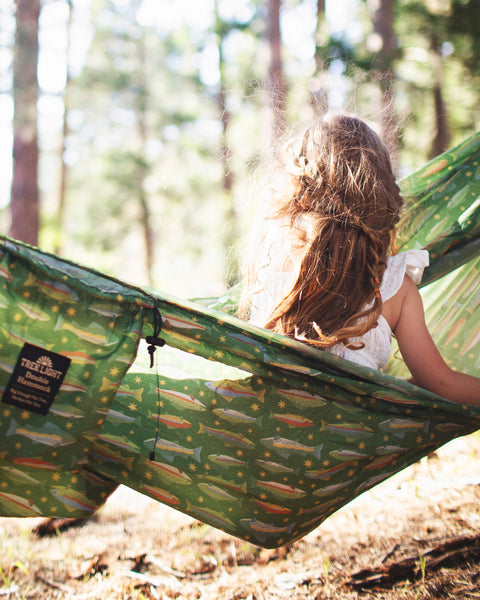 Girl relaxing in a Double Hammock & Pro Hanging Straps (River Trout Print) in a forest setting.