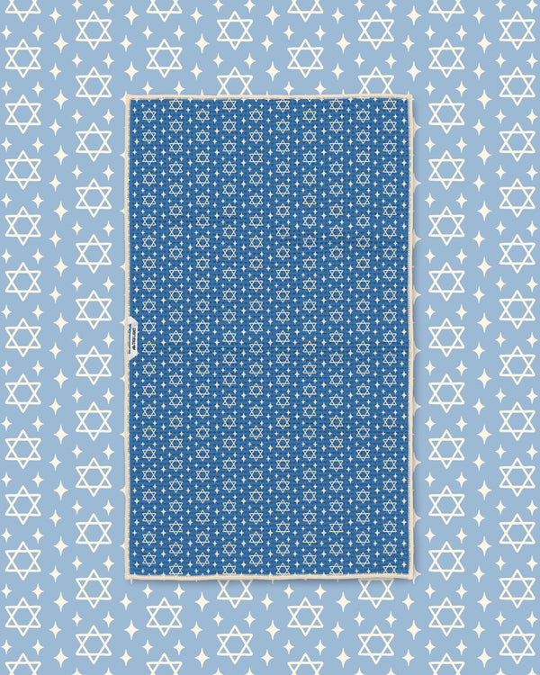 Blue Star of David kitchen towel styled flat on matching light blue star-print background