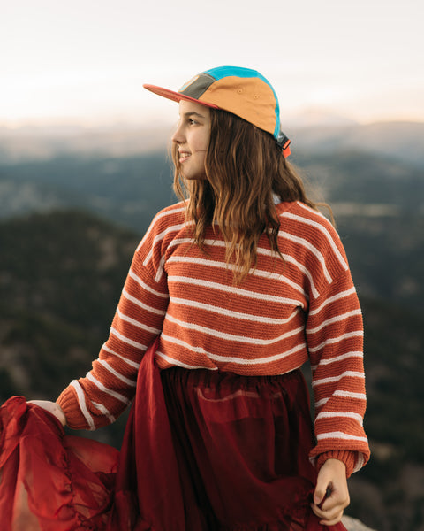Girl wearing the Happiest Camper Kids Hat with a scenic outdoor background.