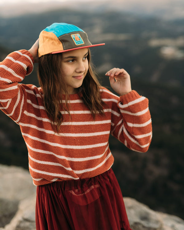 Child wearing Happiest Camper Kids Hat by Trek Light, 5-panel snapback, flat brim, colorful design, outdoors adventure spirit.